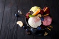 Bowl with ice cream with three different scoops of white, yellow, red colors and waffle cone, chocolate, tangerines and