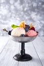 Bowl with ice cream with three different scoops of white, yellow, red colors and waffle cone, chocolate, tangerines and