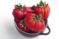 Bowl of imperfect ripe strawberries on white background