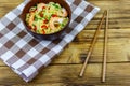 Bowl of instant Chinese noodles with shrimps, green onion and red hot chilli peppers on wooden table Royalty Free Stock Photo