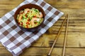 Bowl of instant Chinese noodles with shrimps, green onion and red hot chilli peppers on wooden table Royalty Free Stock Photo