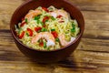 Bowl of instant Chinese noodles with shrimps, green onion and red hot chilli peppers on wooden table Royalty Free Stock Photo