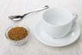 Bowl with instant freeze-dried coffee, empty cup, saucer, spoon