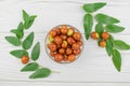 Bowl with jojoba fruits on a white table. Juicy fruits of Chinese date and green leaves on the table