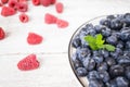 A bowl with juicy and tasty blueberries with fresh mint leaves stands on a white wooden table. Royalty Free Stock Photo