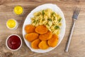 Bowl with ketchup, pepper, salt shakers, fried chicken nuggets with pasta, dill in dish, fork on wooden table. Top view Royalty Free Stock Photo