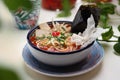 Bowl of Korean, oriental tomato soup, close-up. Kimchi soup with tofu, Japanese noodles and spices. Vegan food.