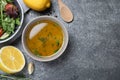 Bowl with lemon dressing near salad on grey table, flat lay with space for text. Delicious salad dressing Royalty Free Stock Photo