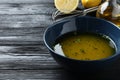 Bowl with lemon sauce on black wooden table, space for text. Delicious salad dressing Royalty Free Stock Photo