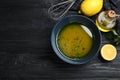 Bowl of lemon sauce and ingredients on black wooden table, flat lay with space for text. Delicious salad dressing Royalty Free Stock Photo