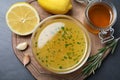 Bowl with lemon sauce and ingredients on dark table, top view. Delicious salad dressing Royalty Free Stock Photo