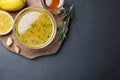 Bowl of lemon sauce and ingredients on dark table, top view with space for text. Delicious salad dressing Royalty Free Stock Photo