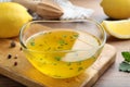 Bowl with lemon sauce and ingredients on wooden table, closeup. Delicious salad dressing Royalty Free Stock Photo