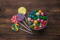 A bowl with lots of candies and lollipops on a wooden background Royalty Free Stock Photo