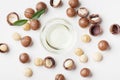 Bowl of macadamia oil and heap of nuts on white table top view. Royalty Free Stock Photo