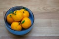 A bowl of mandarin oranges with a green leaf and water drops. Ripe sour citrus fruit on a wooden table. Handful of orange