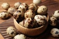 Bowl and many speckled quail eggs on table, closeup