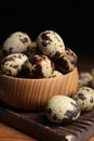 Bowl and many speckled quail eggs on table, closeup