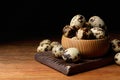 Bowl and many speckled quail eggs on wooden table.