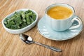 Bowl with marmalade in form green bean, coffee in cup on saucer, spoon on wooden table Royalty Free Stock Photo