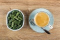 Bowl with marmalade in form green bean, coffee in cup, spoon on saucer on wooden table. Top view Royalty Free Stock Photo