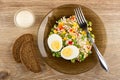 Bowl with mayonnaise, bread, plate with vegetable mix and boiled eggs, fork on table. Top view Royalty Free Stock Photo