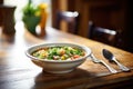 bowl of minestrone with spoon on wooden table