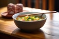 bowl of minestrone with spoon on wooden table