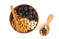 A bowl of mixed nuts and dried fruit is shown with two wooden spoons on a white background Royalty Free Stock Photo
