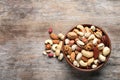 Bowl with mixed organic nuts on wooden background, top view. Royalty Free Stock Photo