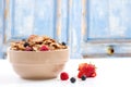 A bowl of muesli breakfast cereal and milk with berries on a blue rustic woodbackground Royalty Free Stock Photo