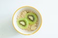 Bowl of muesli with fresh fruits. From above view of white ceramic bowl of muesli with slices of fresh kiwi fruit on white