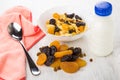 Bowl with muesli, heap of dried fruits, yogurt, spoon
