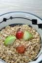 A bowl of muesli with pieces of apple and grapes