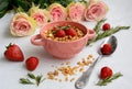 Bowl with muesli, strawberries, rosemary and roses on a light background Royalty Free Stock Photo