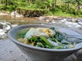 A bowl noodle beside the river