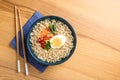 Bowl of noodles with broth, egg, vegetables and chopsticks served on wooden table, flat lay. Royalty Free Stock Photo