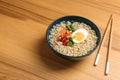 Bowl of noodles with broth, egg, vegetables and chopsticks served on wooden table. Royalty Free Stock Photo