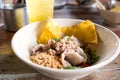 A bowl of noodles filled with meatball, pork, vegetable, peanut