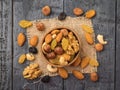 A bowl of nut mixture on a piece of burlap on a wooden table. Flat lay Royalty Free Stock Photo