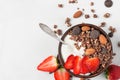 Bowl of oat chocolate granola with yogurt, fresh strawberries and nuts with a spoon on white marble background Royalty Free Stock Photo