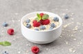 Bowl of oat granola with fresh raspberries, blueberries and mint for healthy breakfast, top view. Portion of cereal garnished