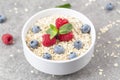 Bowl of oat granola with fresh raspberries, blueberries and mint for healthy breakfast, top view. Portion of cereal garnished