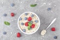 Bowl of oat granola with fresh raspberries, blueberries and mint for healthy breakfast, top view. Portion of cereal garnished