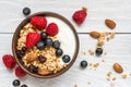 Bowl of oat granola with yogurt, fresh raspberries, blueberries and nuts