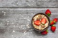 Bowl of oat muesli with strawberry, granola and nutsl on rustic