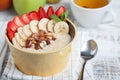 Bowl of oatmeal with a banana, strawberries, almonds, hazelnuts and butter on a rustic table. Hot and a healthy dish for Breakfast Royalty Free Stock Photo