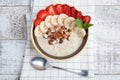 Bowl of oatmeal with a banana, strawberries, almonds, hazelnuts and butter on a rustic table. Hot and a healthy dish for Breakfast Royalty Free Stock Photo