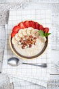 Bowl of oatmeal with a banana, strawberries, almonds, hazelnuts and butter on a rustic table. Hot and a healthy dish for Breakfast Royalty Free Stock Photo