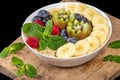 Bowl of oatmeal with blueberries, banana, kiwi, raspberries and mint on wooden kitchen board, close-up Royalty Free Stock Photo